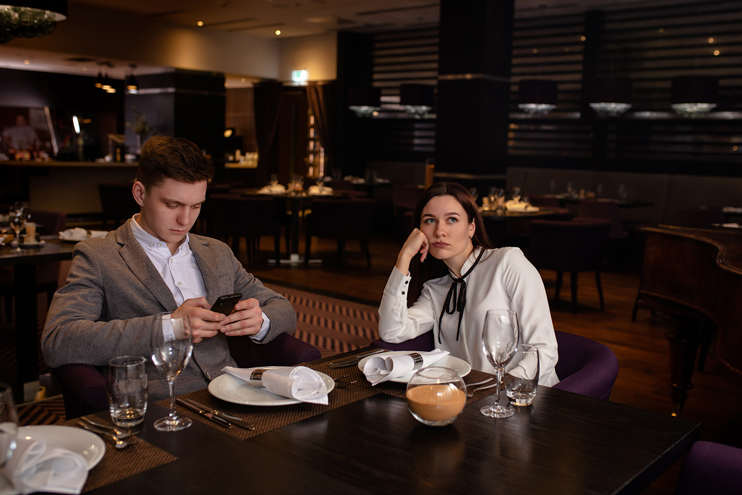 Junger Mann und junge Frau gelangweilt am Restauranttisch